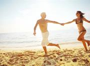 Giovane coppia felice che corre sulle spiagge del Friuli Venezia Giulia