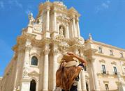 Turista  visita la città di Siracusa, sullo sfondo la Cattedrale Barocca